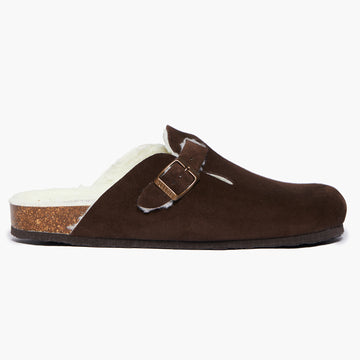 A dark brown suede slipper with a textured sole and an adjustable strap. Handmade in Spain